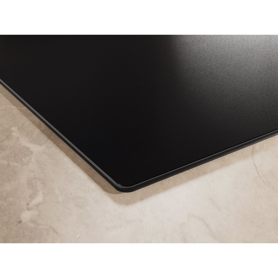Close up of a matte black induction cooktop on a light marble countertop