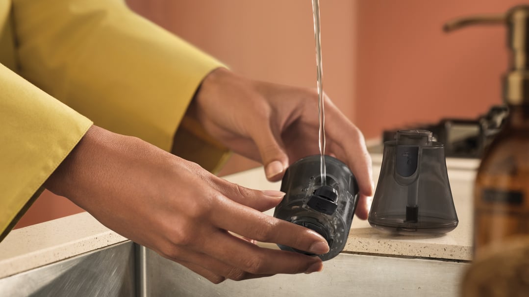 Hands filling the water tank of a Philips handheld garment steamer