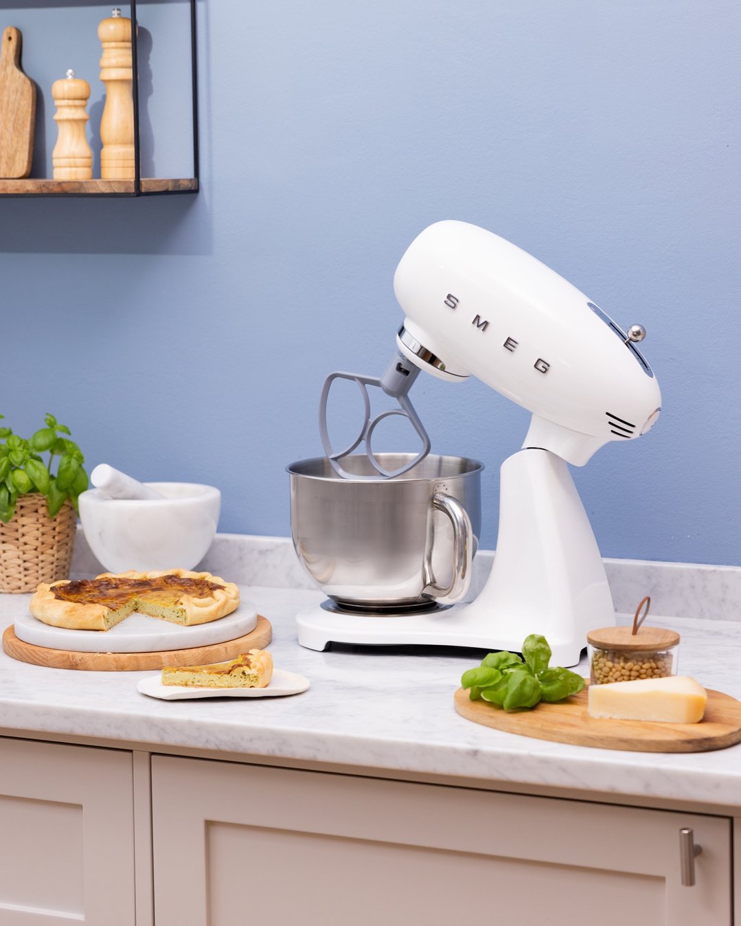 White Smeg stand mixer on a kitchen counter with food and ingredients