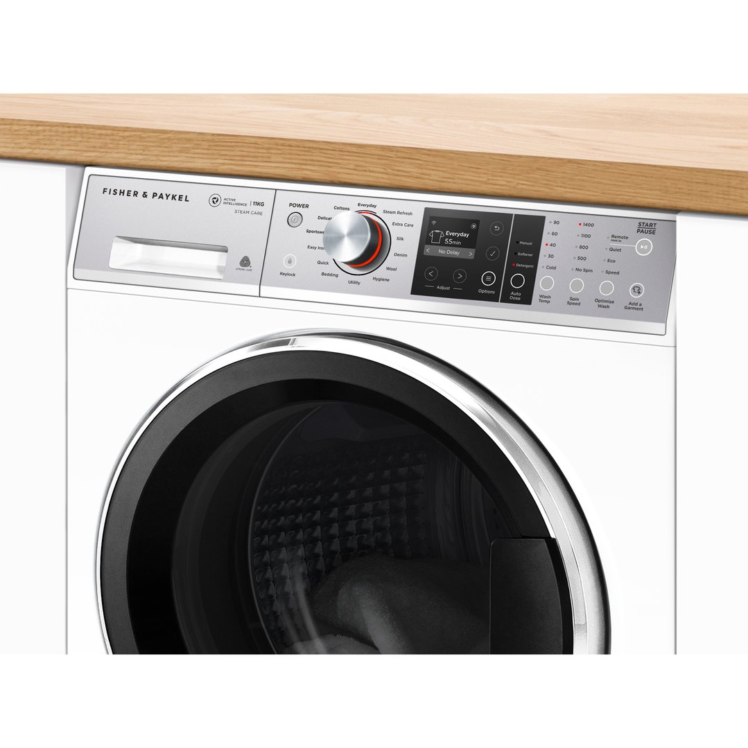 Close-up of a white Fisher & Paykel washing machine under a wooden countertop