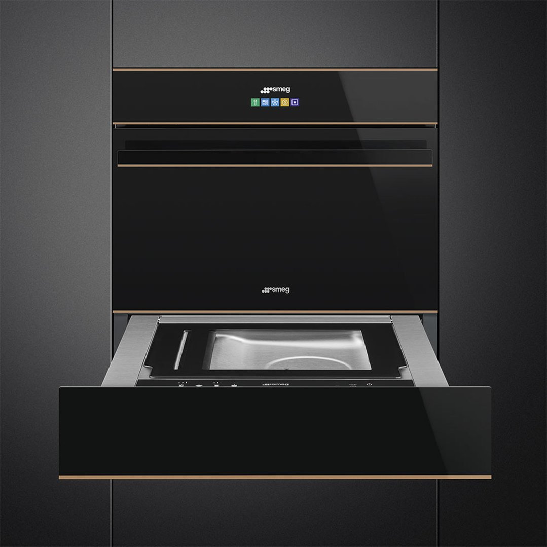 Black built-in oven and warming drawer with a gold trim in a dark kitchen