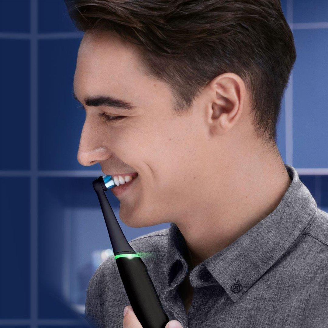 Man brushing teeth with a black electric toothbrush in a bathroom
