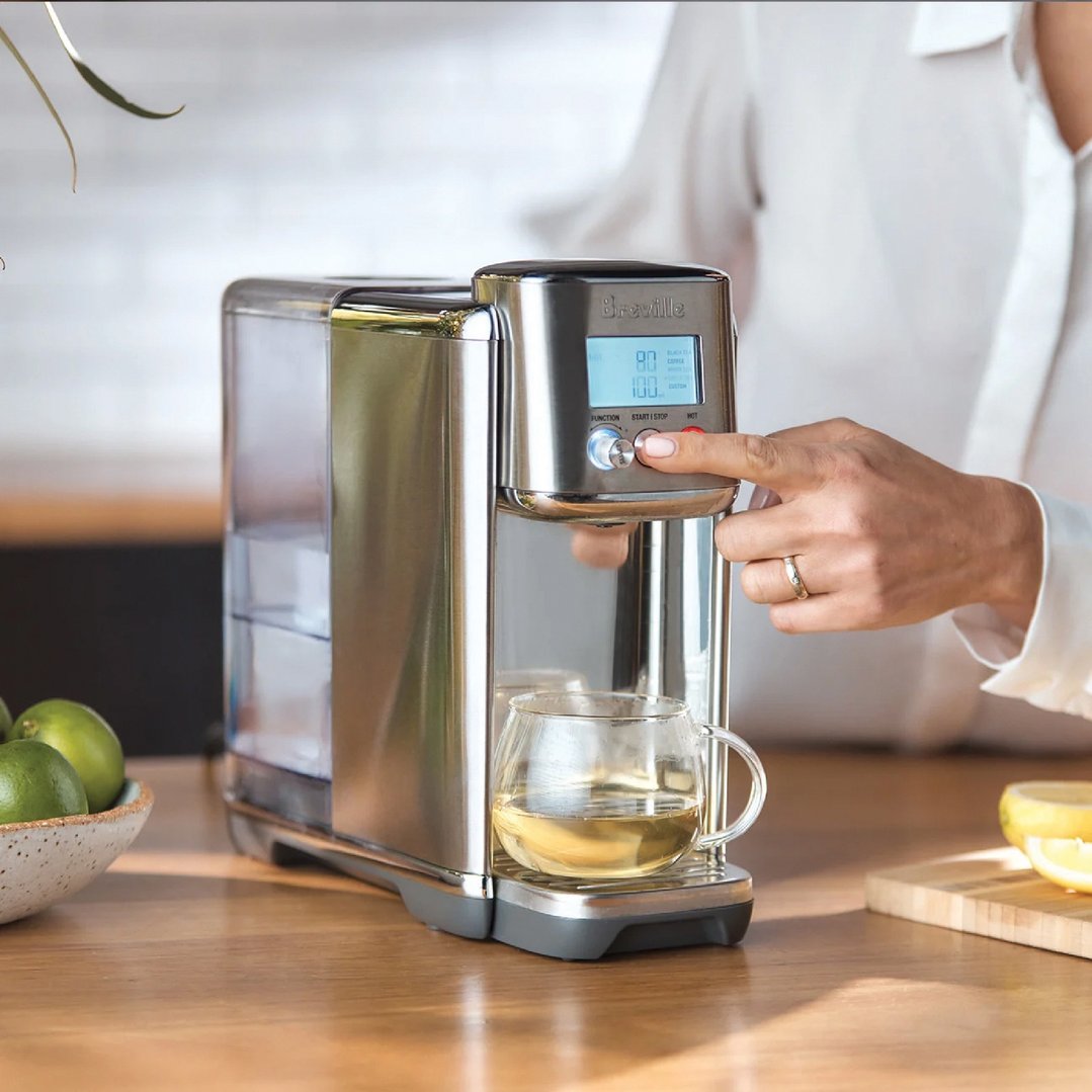 Person's hand pressing a button on the Breville AquaStation Hot Water Dispenser