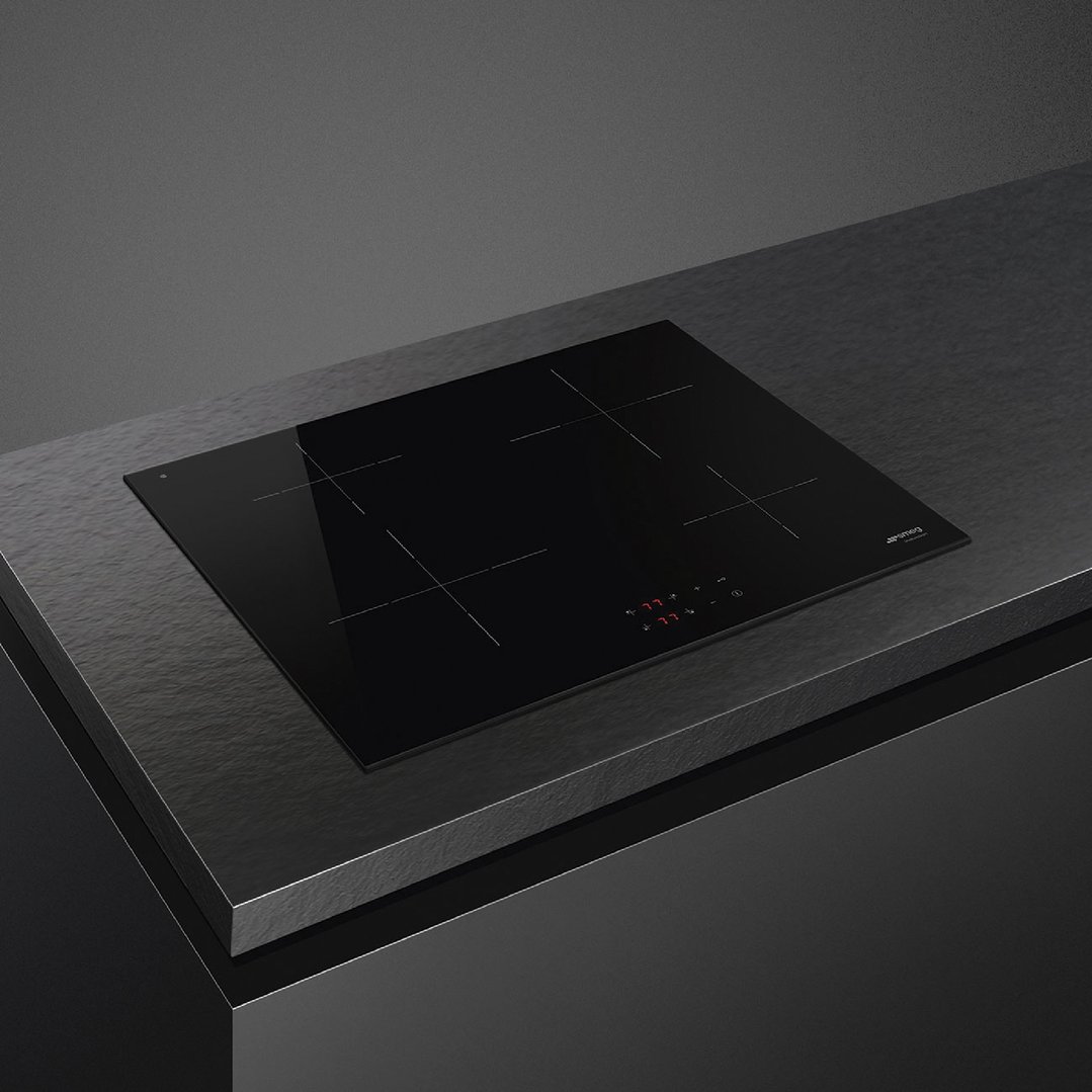 Black induction cooktop with four cooking zones built into a dark countertop