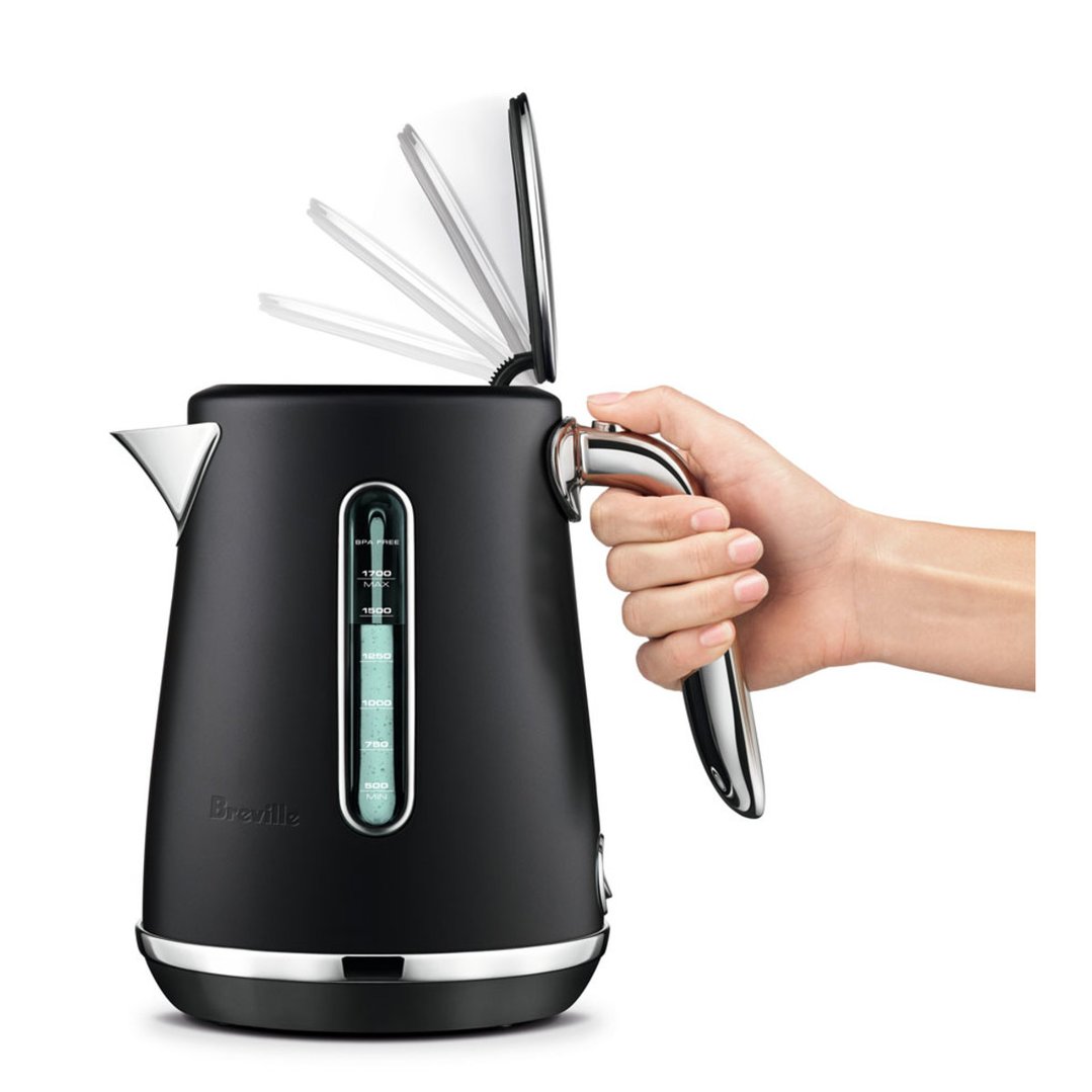 Hand opening the lid of a black Breville kettle, showing water level