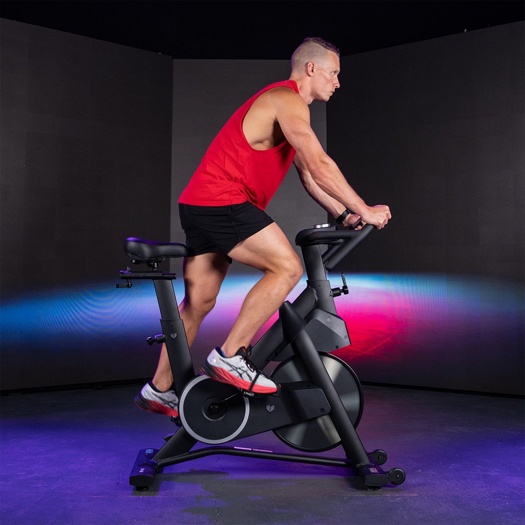 Man in red tank top riding a spin bike