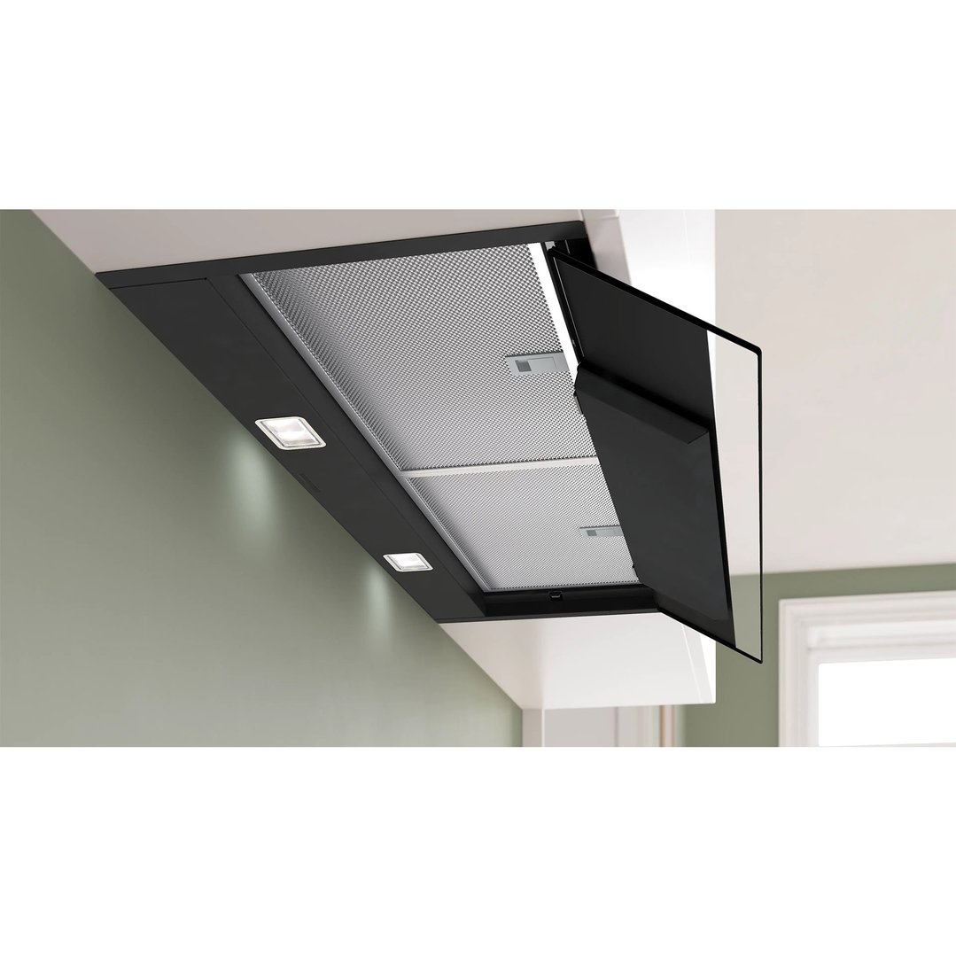 Black integrated rangehood with lights on, installed in a kitchen setting