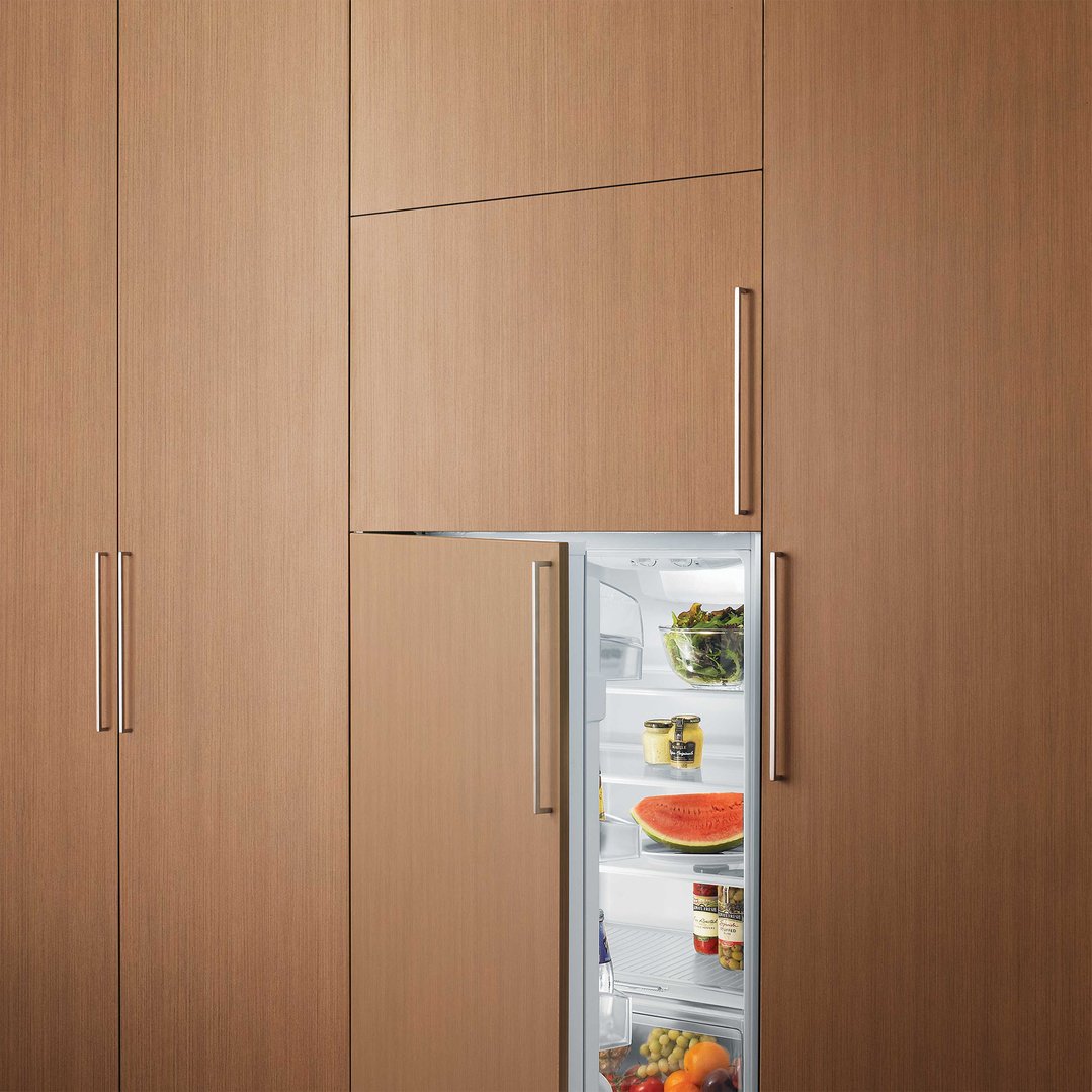 Integrated fridge with open door showing food items in a wooden kitchen