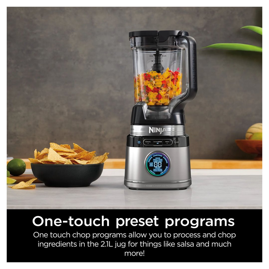 Ninja blender with salsa in the jug, next to a bowl of tortilla chips