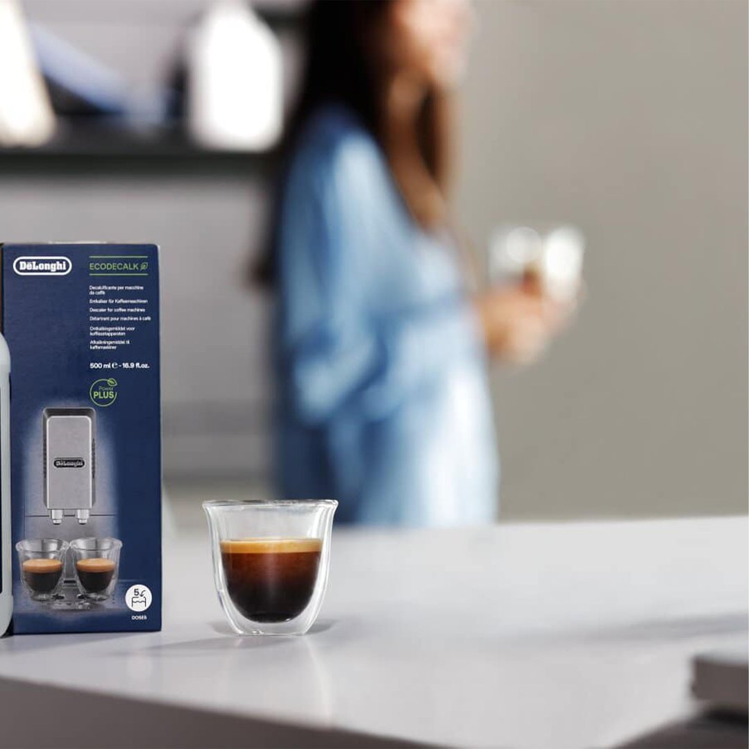 Coffee Descaler box and espresso cup on a counter with a person in background