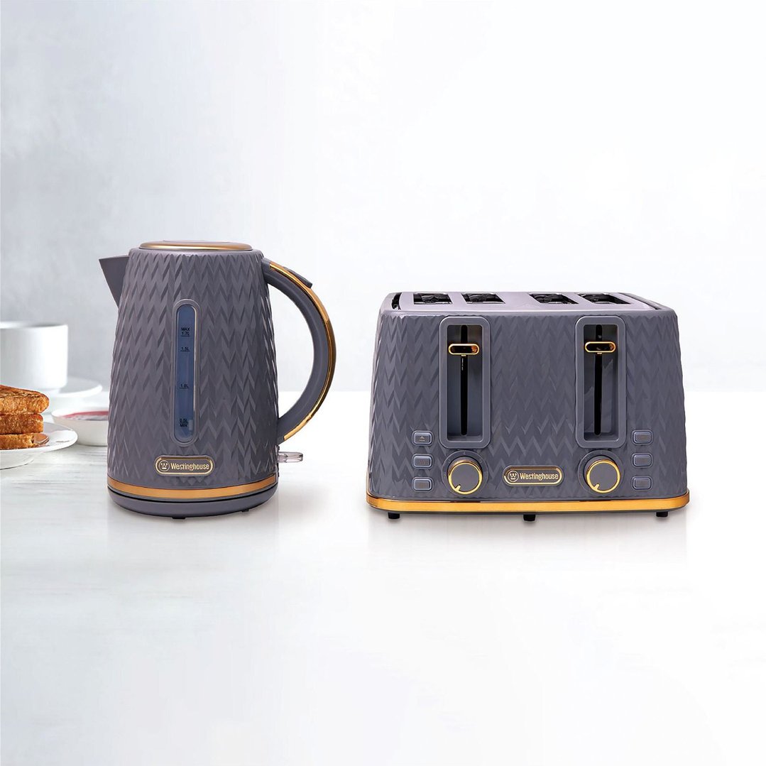 Grey and gold kettle and toaster on a white bench with toast and jam
