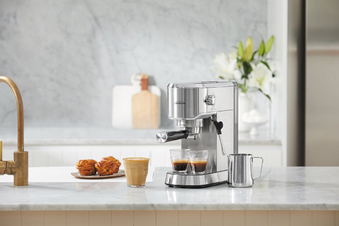 Sunbeam Compact Barista Espresso Machine on a kitchen counter with coffee and pastries