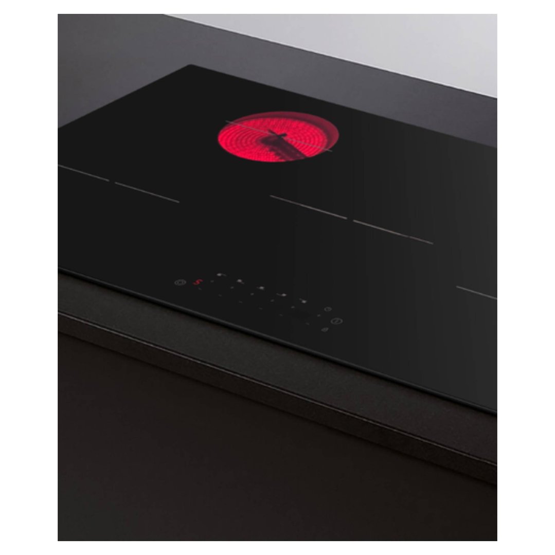Black electric cooktop with one red glowing hob in a kitchen setting