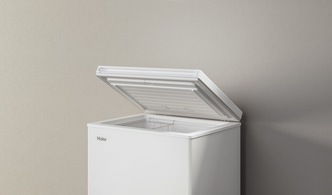 White Haier chest freezer with the lid open, against a neutral wall