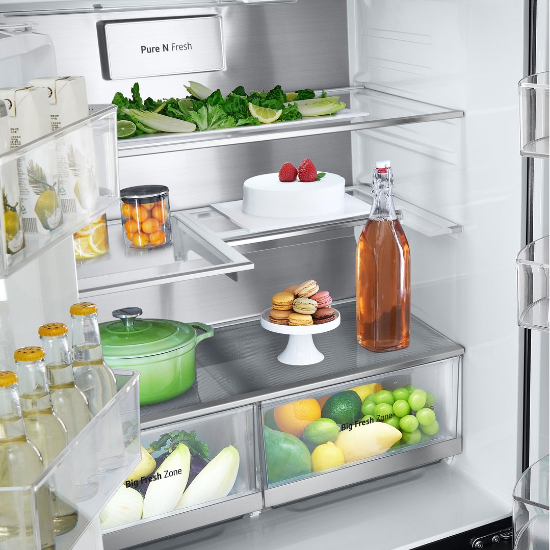 Open fridge interior filled with food, drinks, and a cake