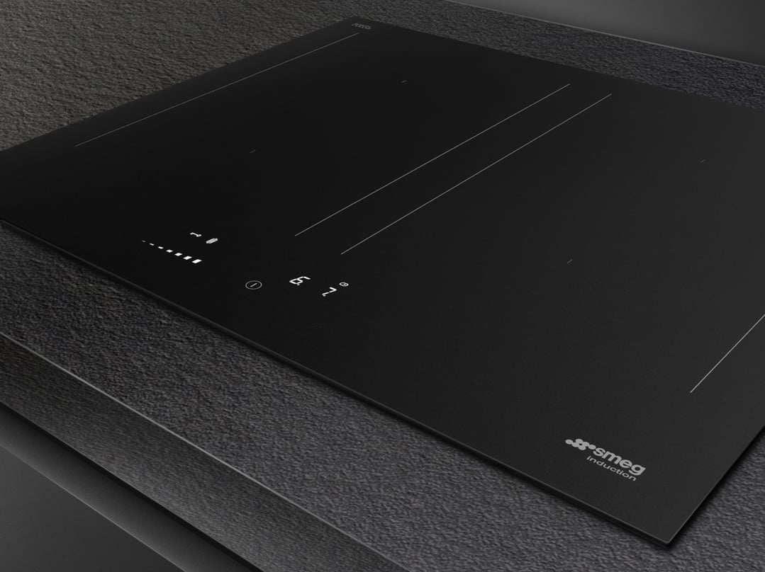 Matte black induction cooktop with controls illuminated in a dark kitchen setting
