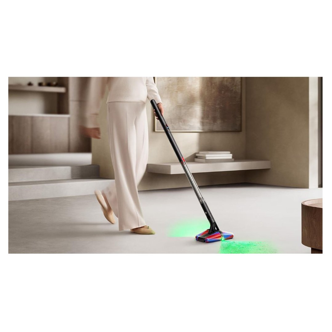 Woman using a handStickVacuum with green laser detection on a light floor