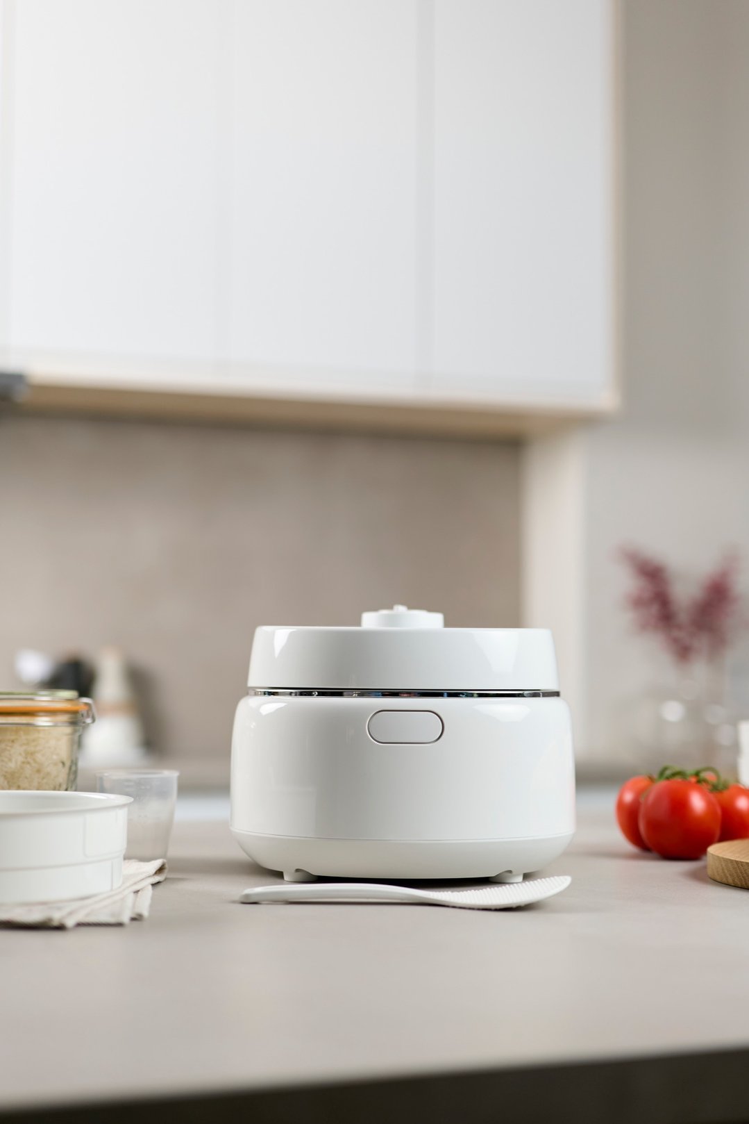 White Panasonic rice cooker on a kitchen counter with tomatoes and rice