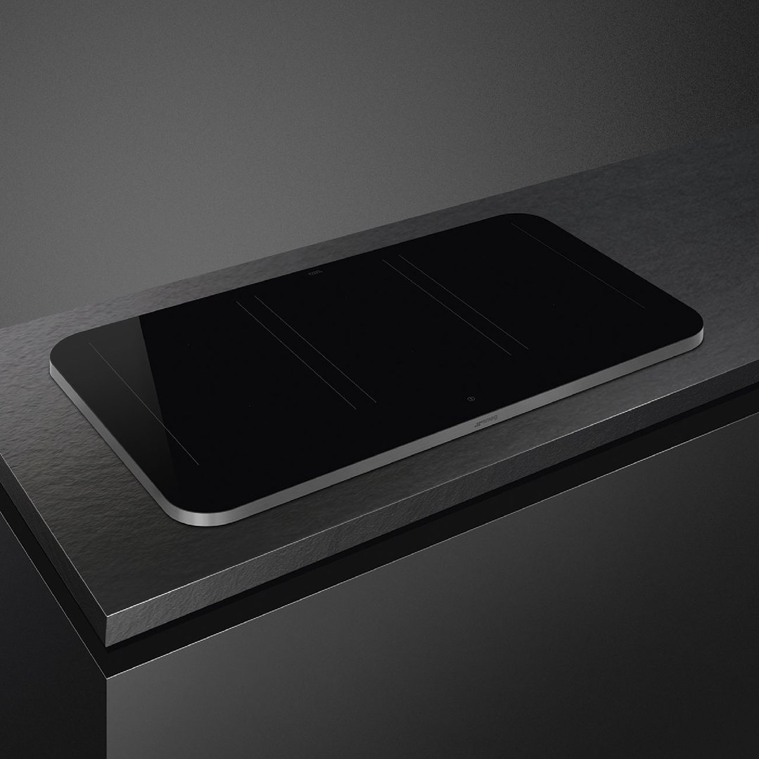 Black induction cooktop with stainless steel trim on a dark countertop
