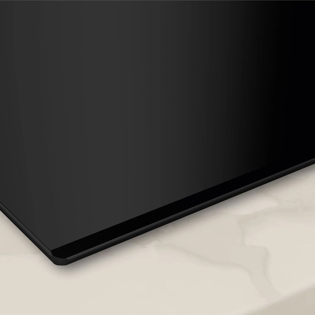 Close up of a black induction cooktop on a light-colored countertop