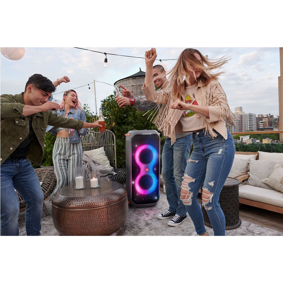 Four people dancing around a JBL PartyBox 710 Party Speaker on a rooftop