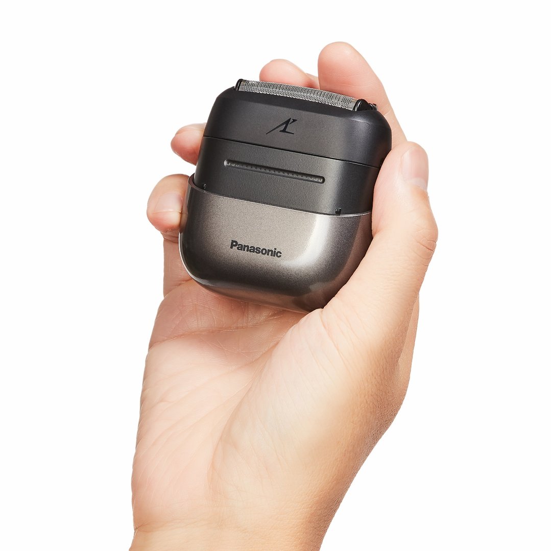 Hand holding a black and grey Panasonic compact shaver