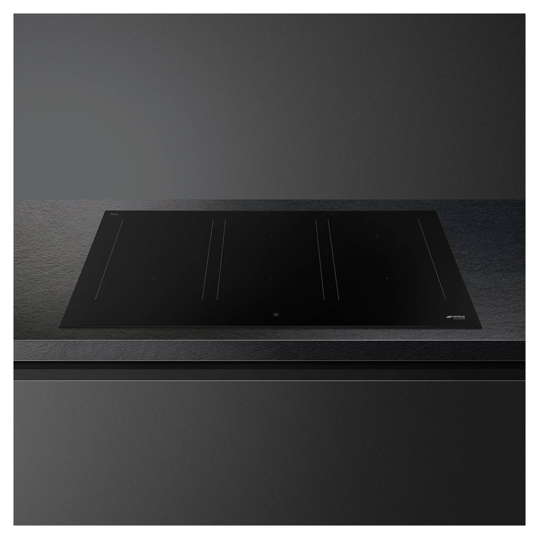 Black induction cooktop built into a dark countertop in a modern kitchen