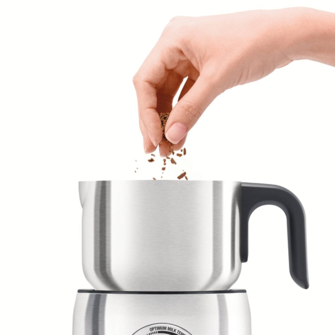 Hand sprinkling chocolate shavings into the Breville Milk Cafe milk frother
