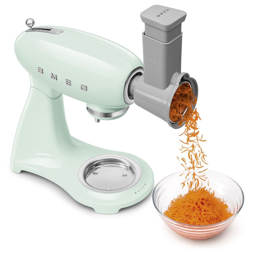 Pastel green Smeg stand mixer with grater attachment shredding carrots into a bowl