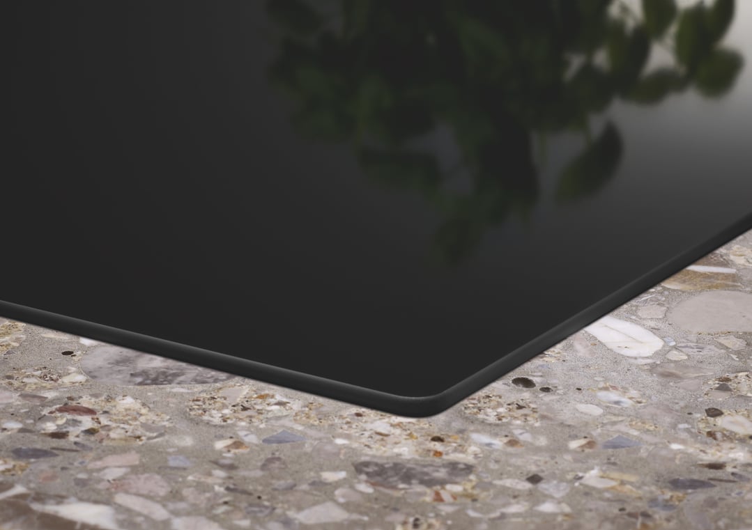 Black induction cooktop installed in a speckled countertop with plant reflection