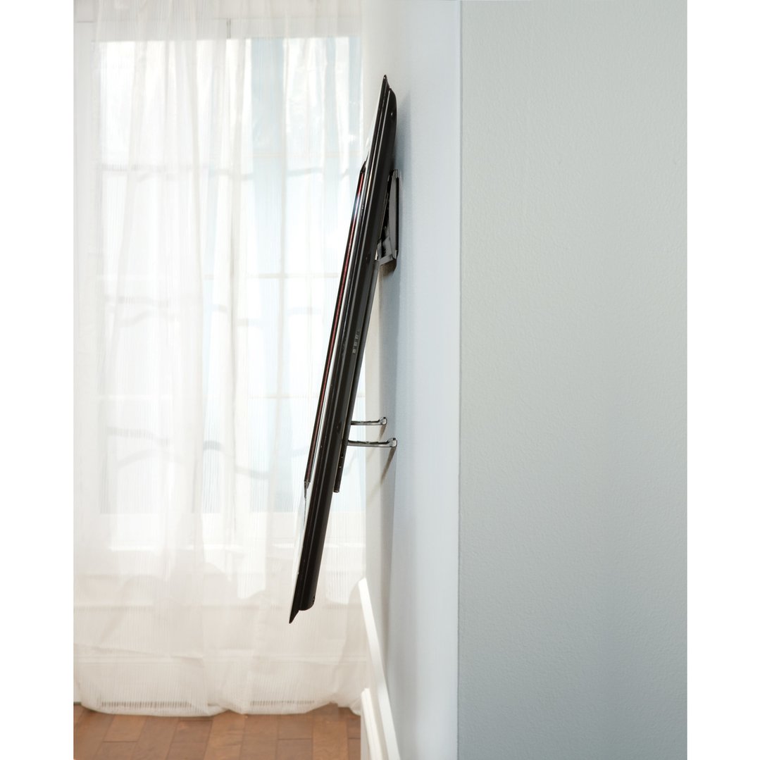 Side view of a wall-mounted TV in a room with sheer curtains