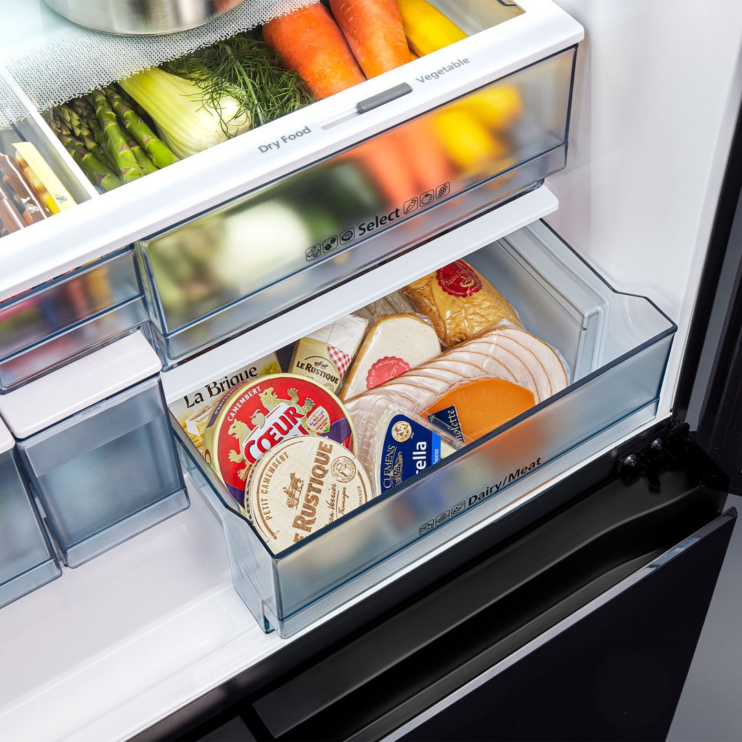Open fridge drawer with cheese, deli meat, and vegetables inside