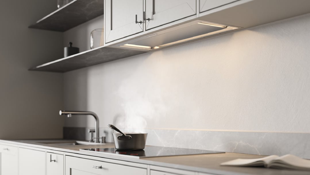 Concealed rangehood integrated into kitchen cabinetry above a cooktop with a pot