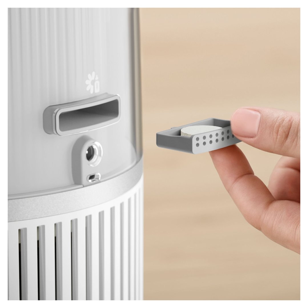 Hand inserting a small white filter into the side of a Philips humidifier