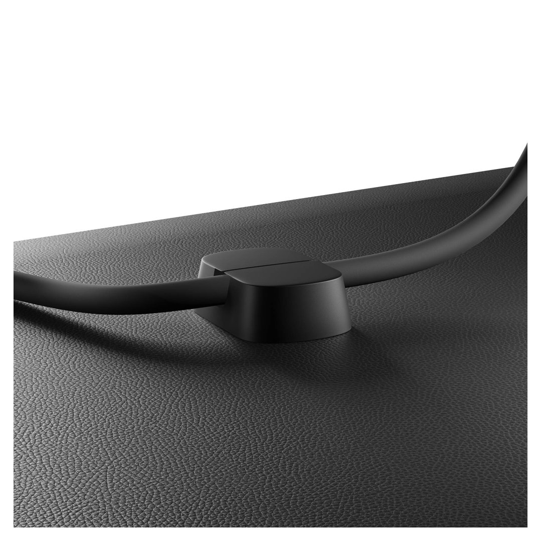 Close-up of a black USB-C cable connected to a black device on a textured surface