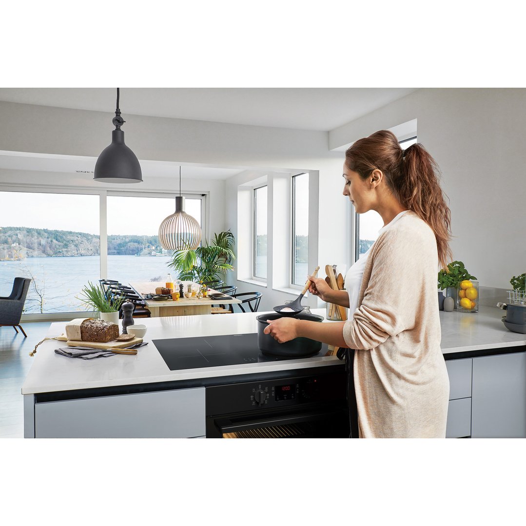 Woman cooking on an induction cooktop in a modern kitchen with a view