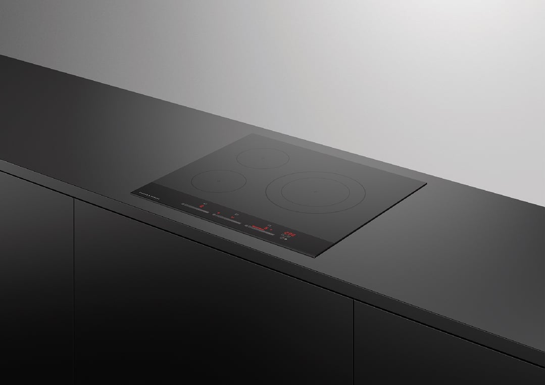 Black induction cooktop with three zones built into a dark kitchen counter