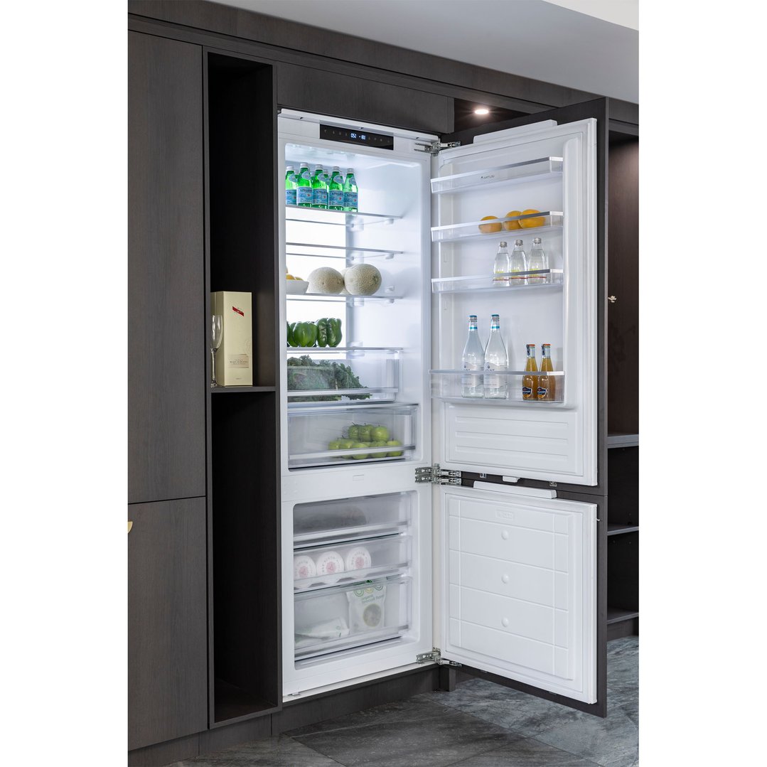 Open integrated bottom mount fridge in a dark wood kitchen cabinet setting