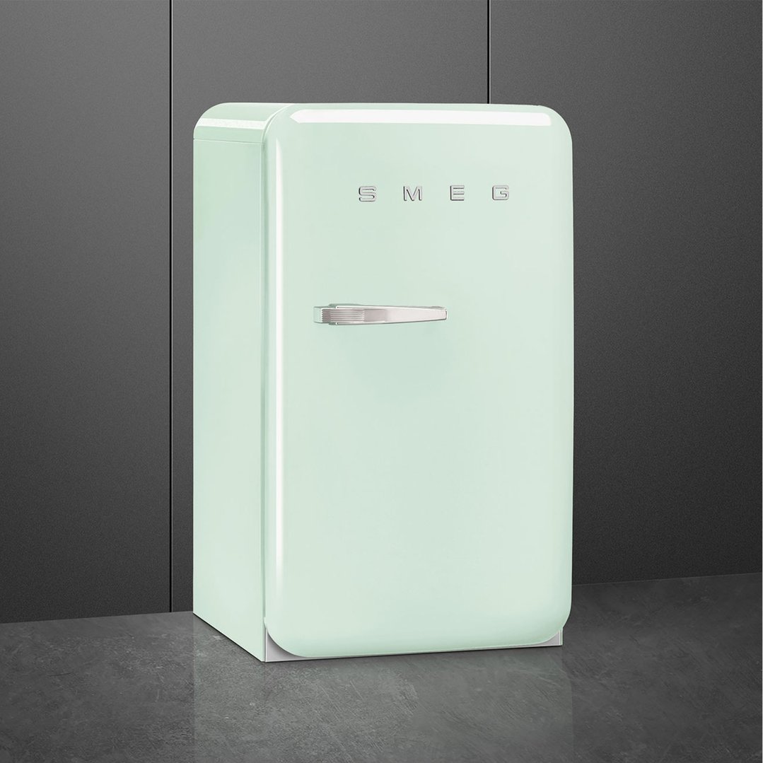 Pastel green SMEG retro refrigerator with right hand hinge in a dark room