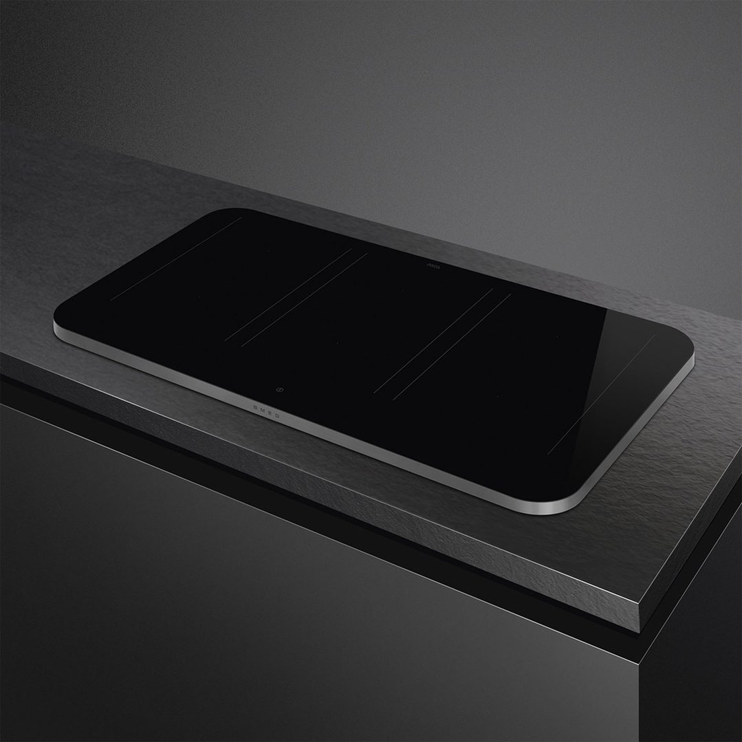 Black induction cooktop with silver trim on a dark countertop