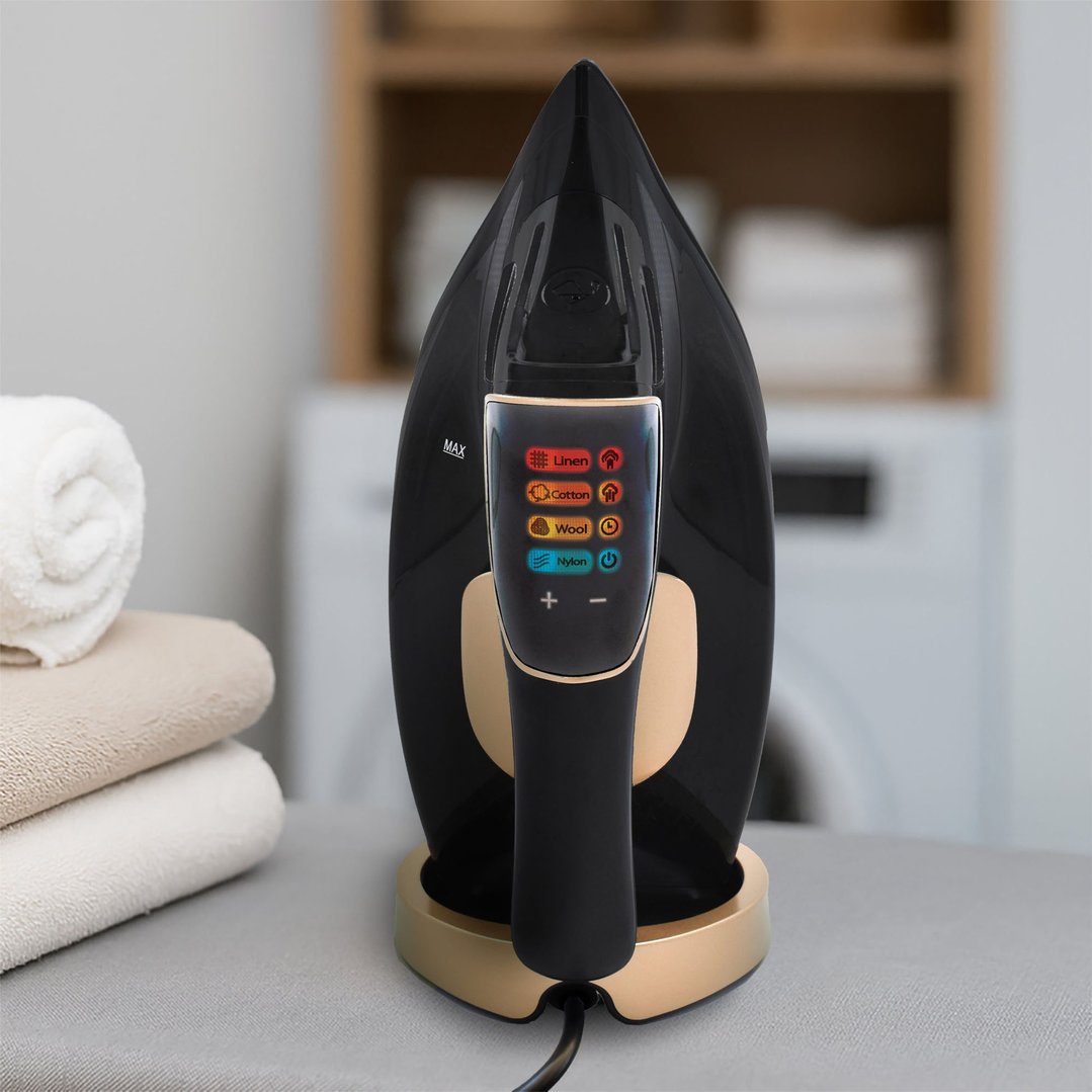 Black and gold steam iron on an ironing board with folded towels