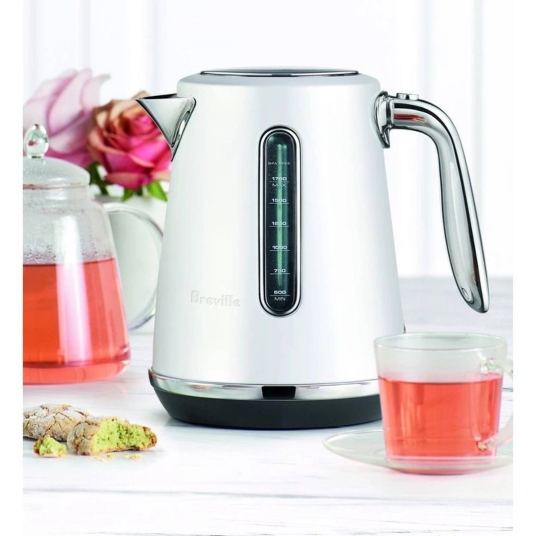 Breville kettle on a white table with tea and cookies