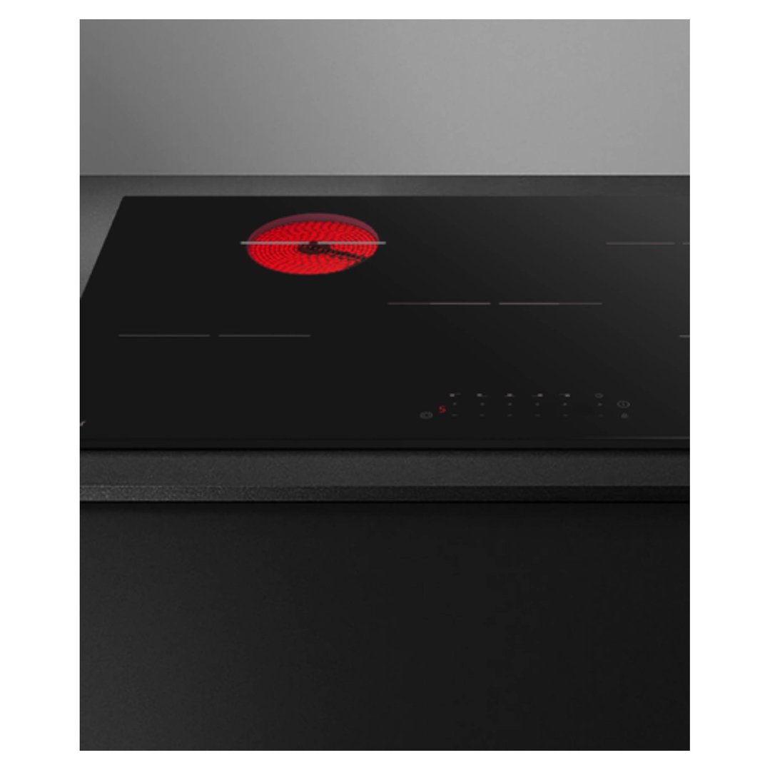 Black electric cooktop with one red glowing hob in a kitchen setting