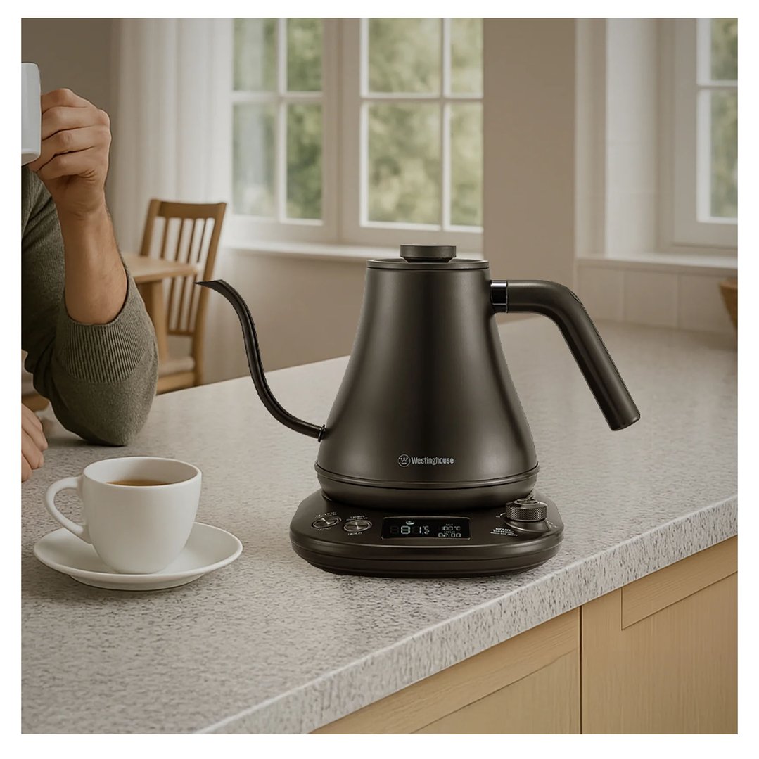 Black stainless steel gooseneck kettle on a kitchen counter with a person and cup