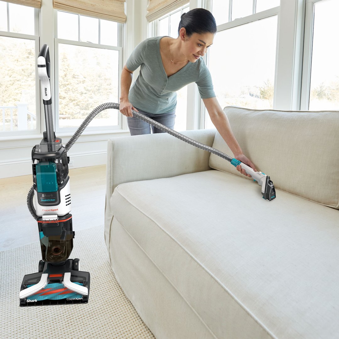 Woman using a Shark CarpetXpert deep carpet cleaner on a white sofa