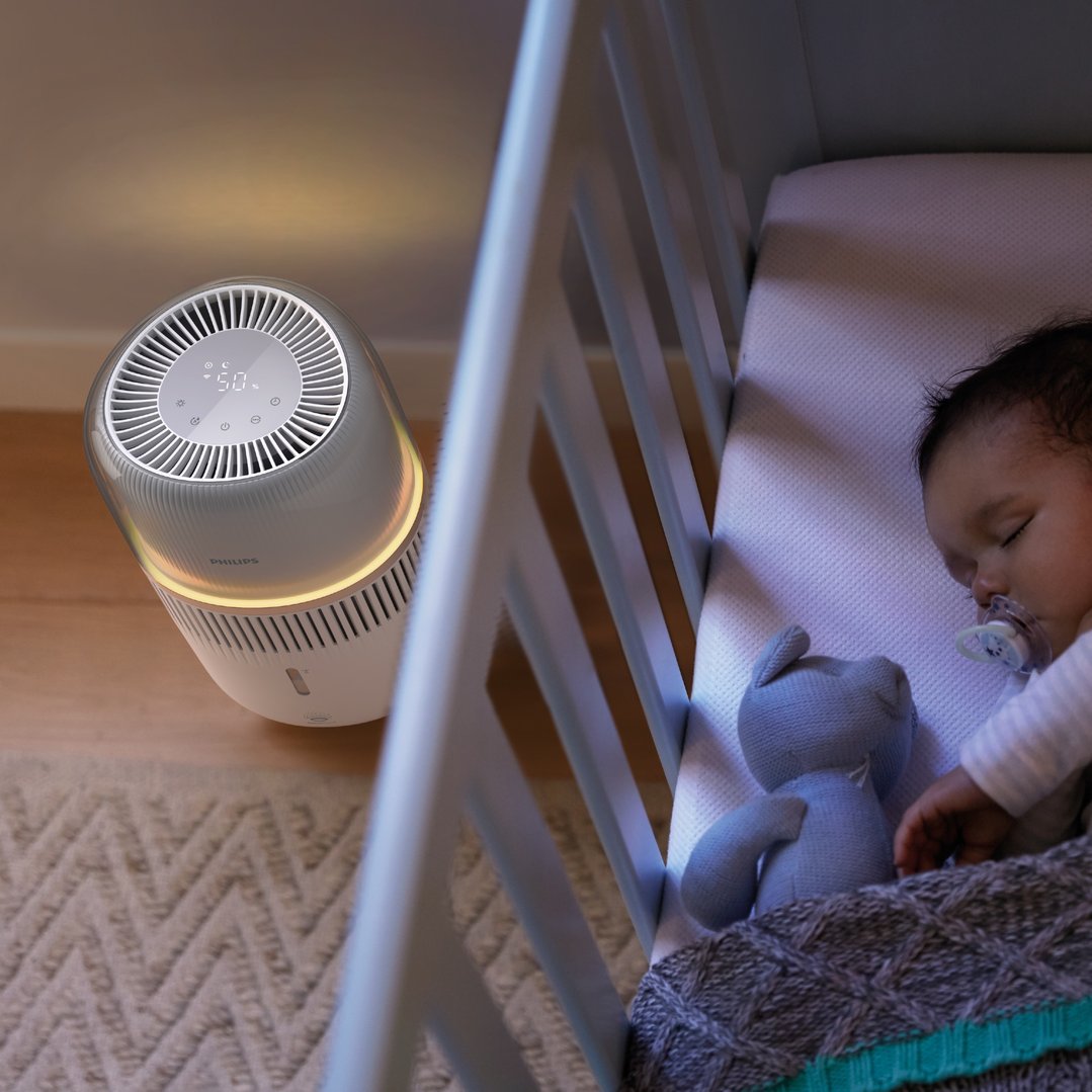 Philips evaporative humidifier next to a baby sleeping in a crib
