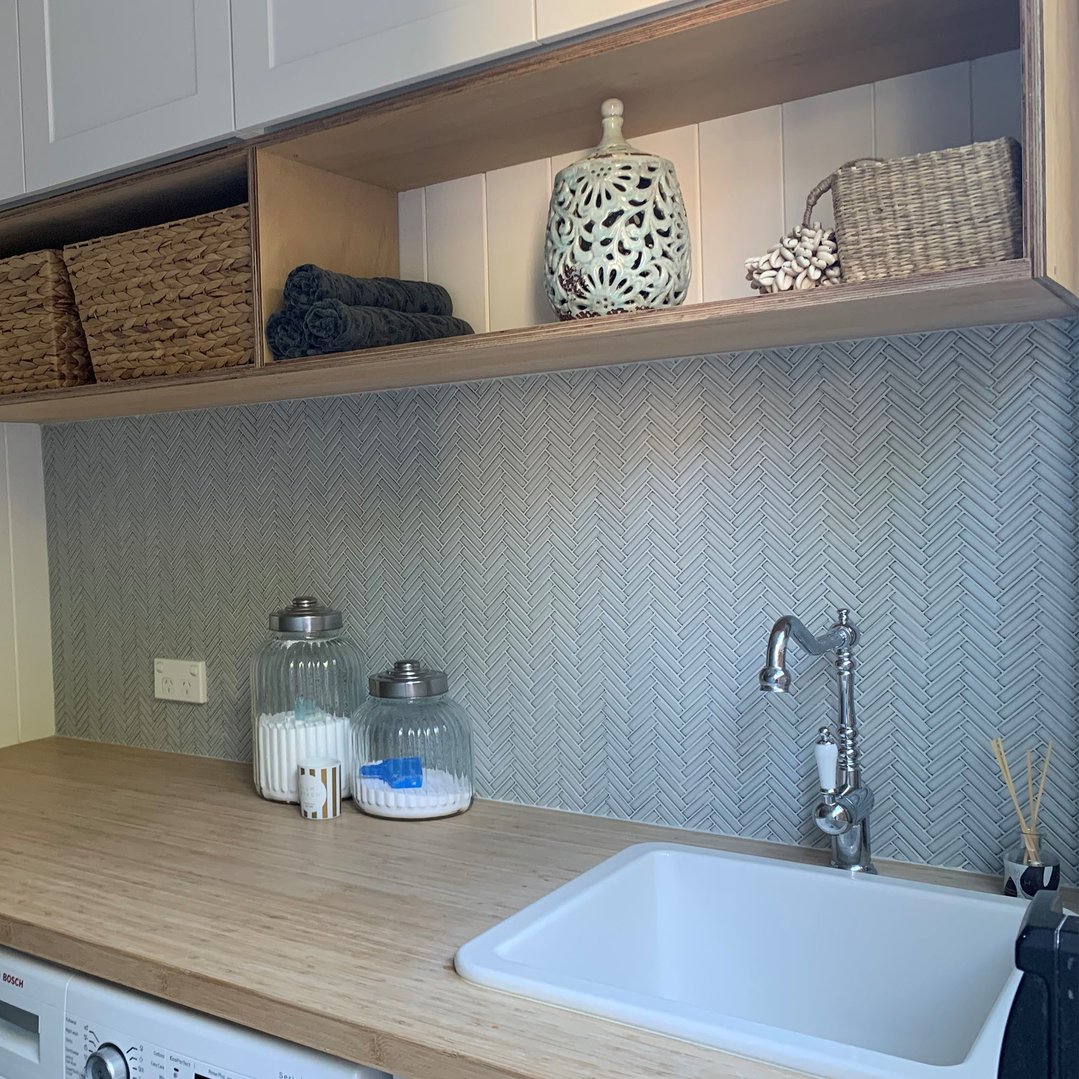 White fireclay sink inset in a wooden countertop in a laundry room