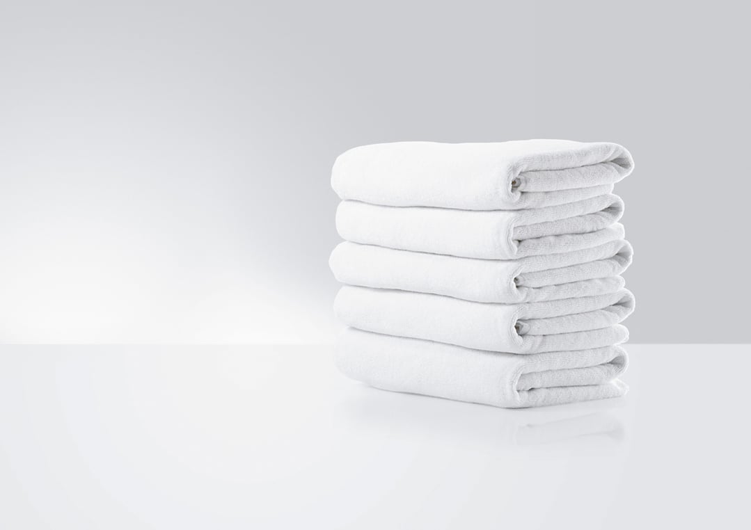 A stack of white folded towels on a white surface