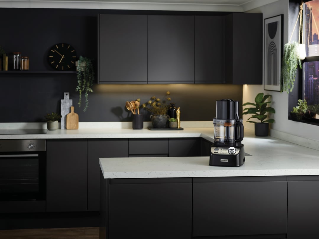 Black food processor on a white countertop in a modern dark kitchen