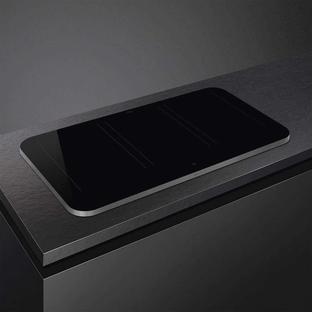 Black induction cooktop with silver trim on a dark countertop in a kitchen